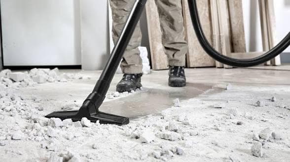 Industrial vacuum removing construction rubble and plaster residue from a floor after building work