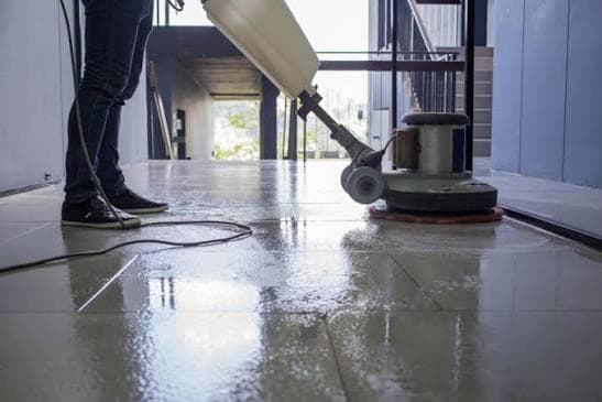 Floor polishing machine restoring reflective tiles in a corridor after construction clean-up